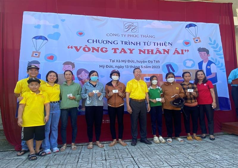 Đại diện Công ty Phúc thắng (áo vàng) và bà Phan Thị Hồng Loan (áo đỏ) Chủ tịch Hội CTĐ huyện Đạ Tẻh trao thẻ bảo hiểm y tế cho người dân