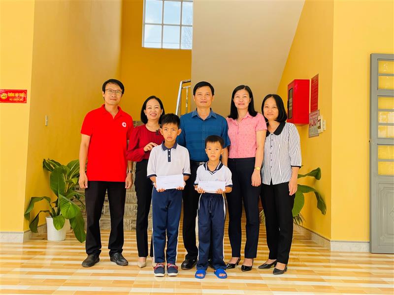 Đại diện Công đoàn Huyện ủy và Hội chữ thập đỏ huyện trao tiền ăn hỗ trợ cho 02 em học sinh trường Tiểu học Lê Lợi