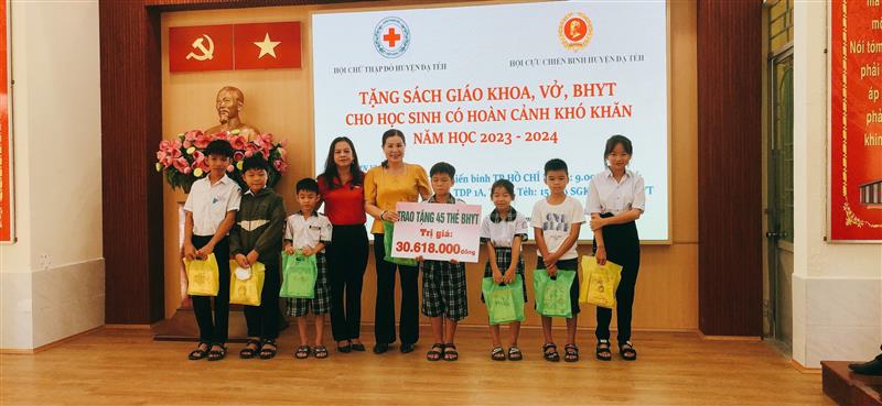 Bà Hoàng Thị Khuyên (nhà hảo tâm, áo vàng) trao thẻ bảo hiểm y tế  cho học sinh có hoàn cảnh khó khăn